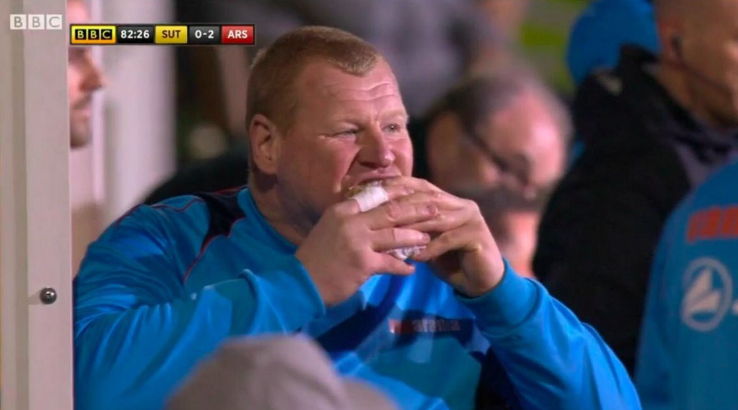 Wayne Shaw digs into a pie on Sutton United's bench